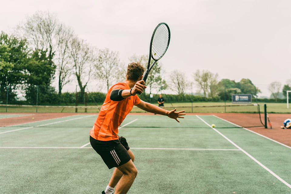 Теннисист в оранжевой футболке