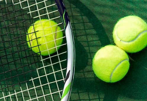 Теннисная ракетка и теннисные мячи лежат на корте