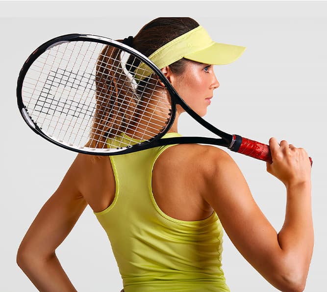 Девушка в салатовой майке и козырьке с теннисной ракеткой на плече